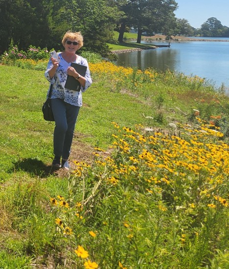 Presenter Katherine McConnell standing next to a shoreline buffer planting with yellow flowers